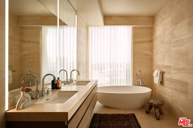 bathroom featuring a bath, a healthy amount of sunlight, and tile walls