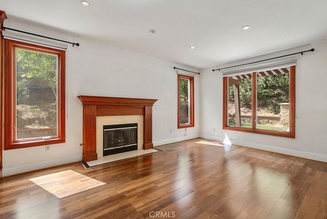 unfurnished living room featuring hardwood / wood-style flooring and a tiled fireplace