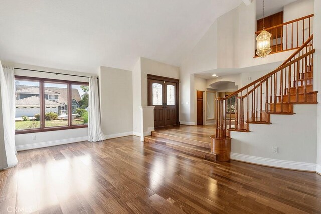 entrance foyer with a chandelier, hardwood / wood-style floors, high vaulted ceiling, and plenty of natural light