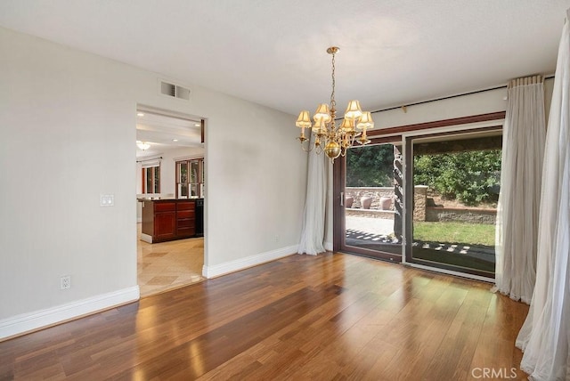 unfurnished dining area with a notable chandelier and light hardwood / wood-style floors