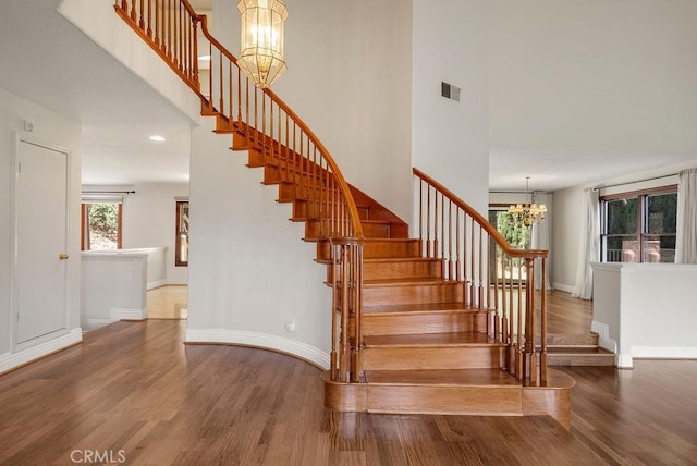 stairway with a chandelier and wood-type flooring