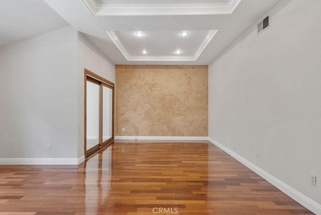 unfurnished room featuring a tray ceiling, hardwood / wood-style floors, and ornamental molding