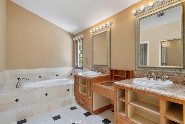 bathroom with tiled bath, tile patterned flooring, vanity, and vaulted ceiling