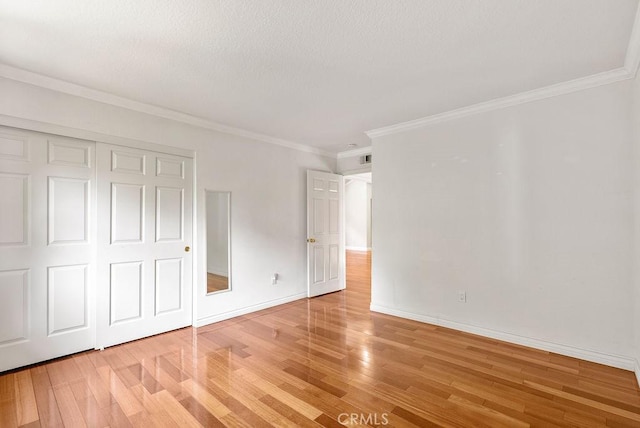 unfurnished bedroom with hardwood / wood-style floors, a closet, and crown molding