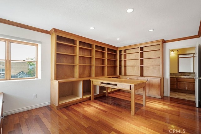 unfurnished office featuring crown molding, sink, and wood-type flooring