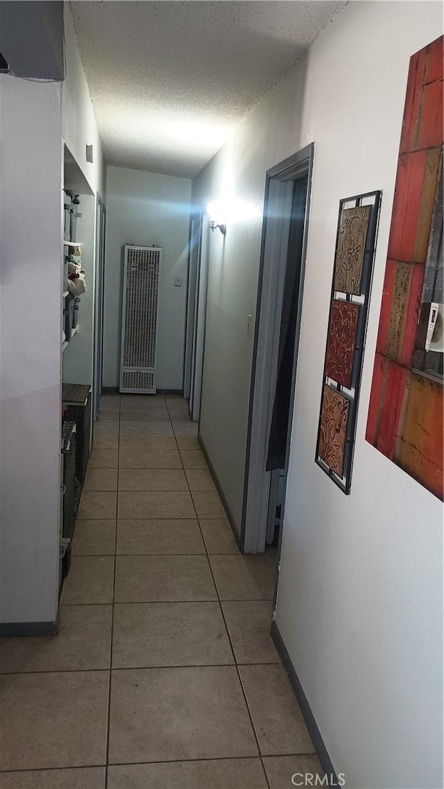 corridor with light tile patterned floors and a textured ceiling