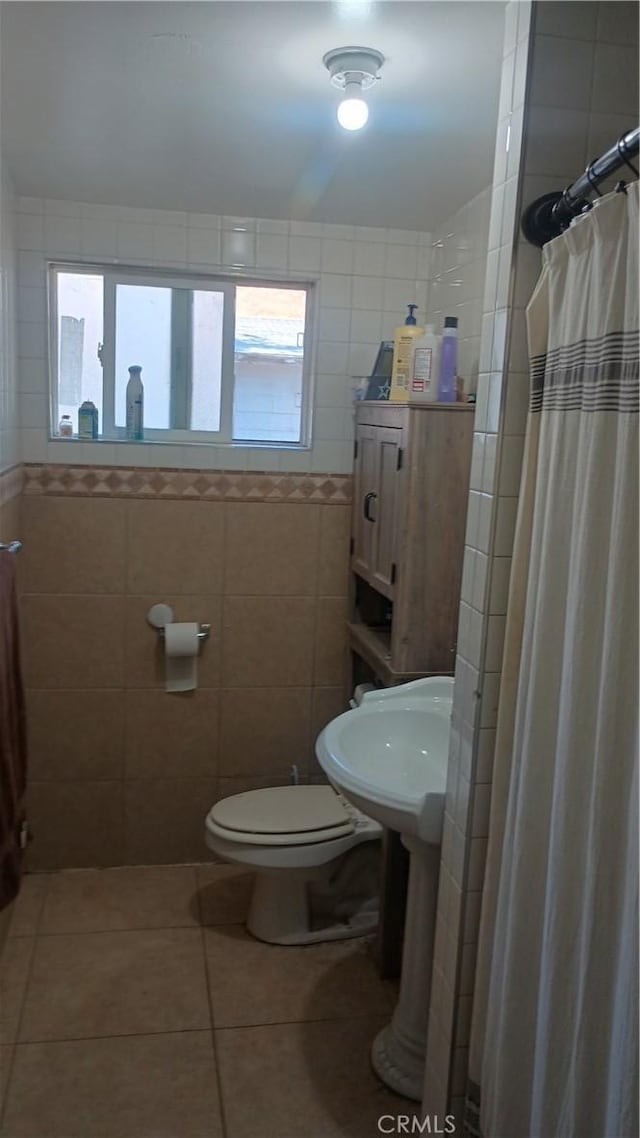 bathroom with a shower with curtain, tile patterned floors, a wealth of natural light, and tile walls