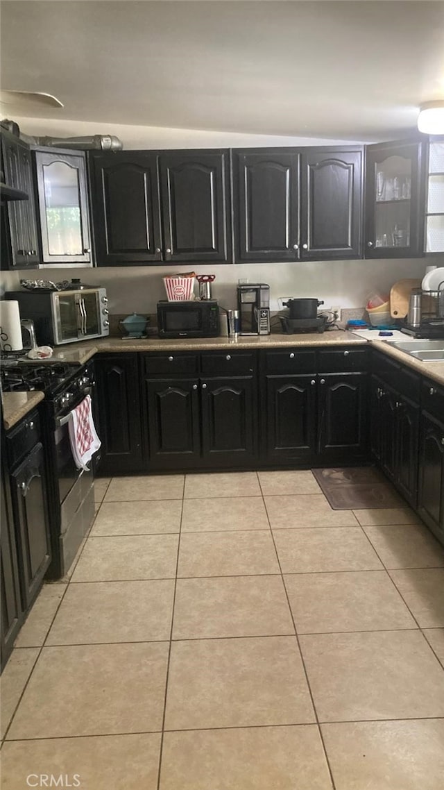 kitchen with light tile patterned flooring, sink, and black appliances