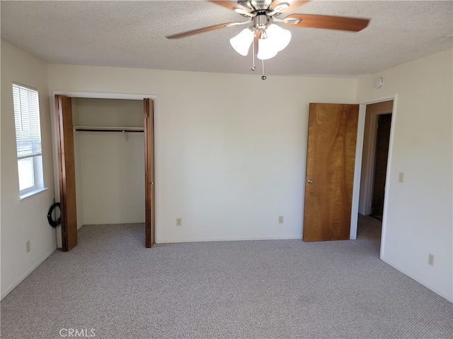 unfurnished bedroom featuring ceiling fan, light carpet, and a textured ceiling