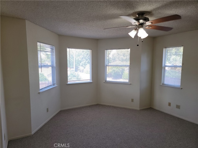 unfurnished room with a wealth of natural light, a textured ceiling, carpet floors, and ceiling fan