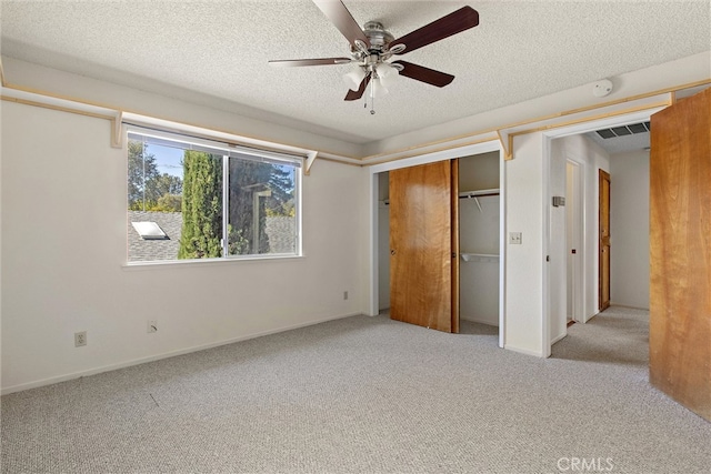 unfurnished bedroom featuring light carpet, a closet, a textured ceiling, and ceiling fan