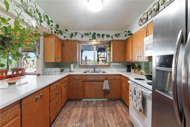 kitchen with white appliances, hardwood / wood-style flooring, and sink