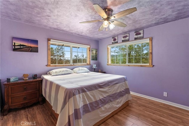 bedroom featuring a textured ceiling, ceiling fan, and wood-type flooring