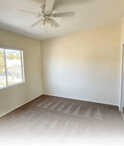 carpeted spare room with ceiling fan