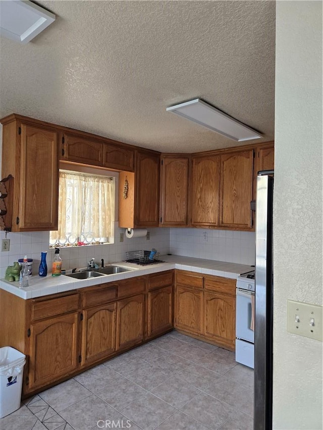 kitchen featuring backsplash, sink, a textured ceiling, and white range