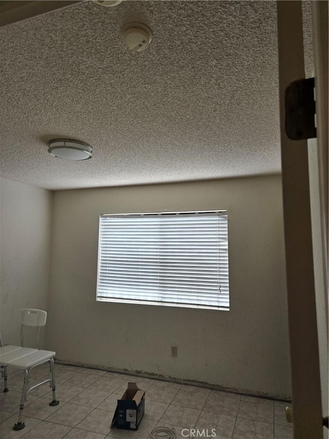 tiled spare room featuring a textured ceiling and a wealth of natural light