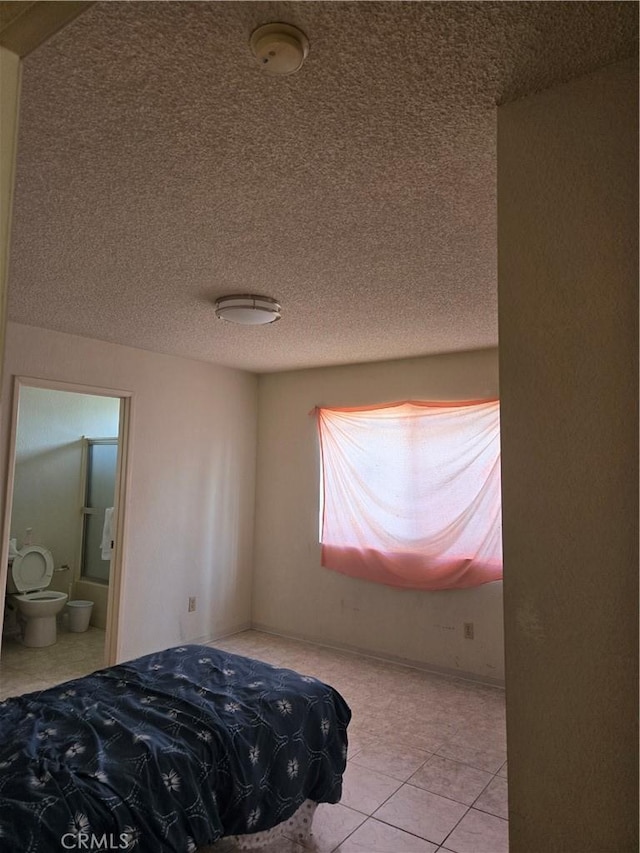 tiled bedroom with a textured ceiling and connected bathroom