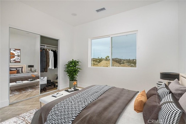 bedroom with light wood-type flooring, baseboards, visible vents, and a closet