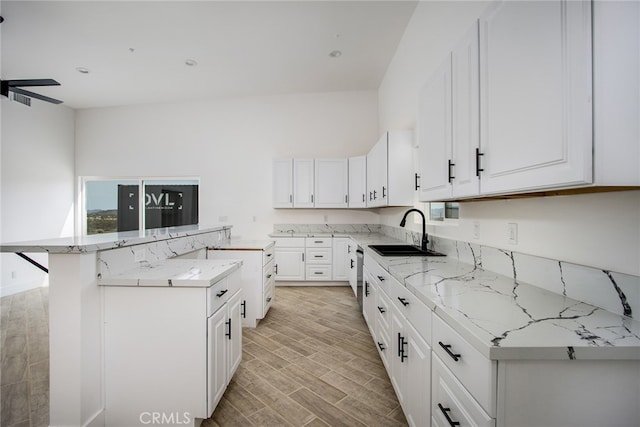 kitchen with light hardwood / wood-style flooring, white cabinetry, a kitchen island, and sink