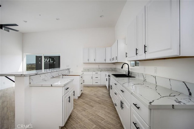 kitchen with wood tiled floor, white cabinets, a kitchen island, and a sink