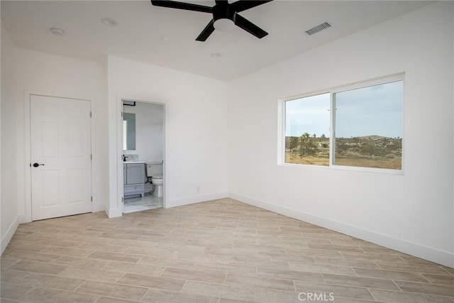 unfurnished bedroom with ensuite bath, baseboards, visible vents, and wood finish floors