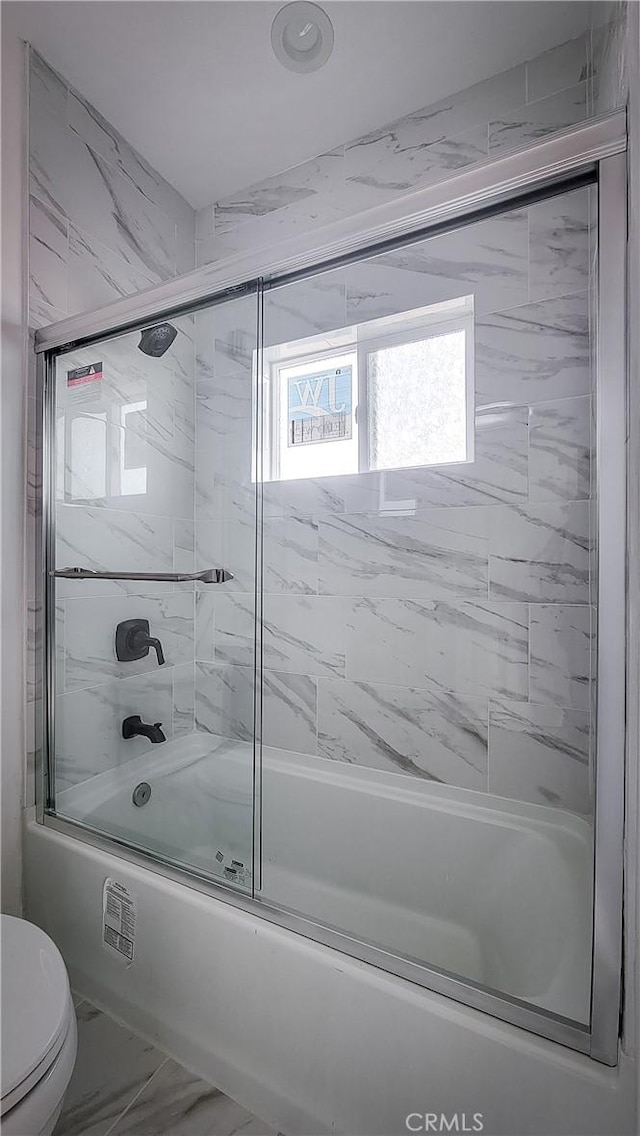 full bath with marble finish floor, shower / bath combination with glass door, and toilet