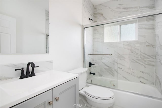 bathroom with vanity, toilet, and bath / shower combo with glass door