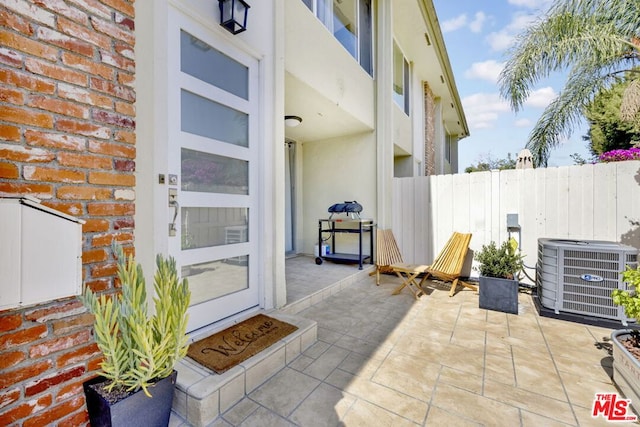 view of exterior entry featuring central AC and a patio area