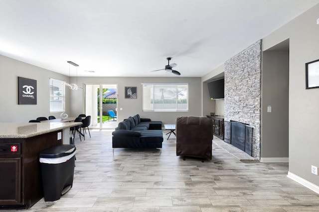 living room with light wood-type flooring, a fireplace, and ceiling fan