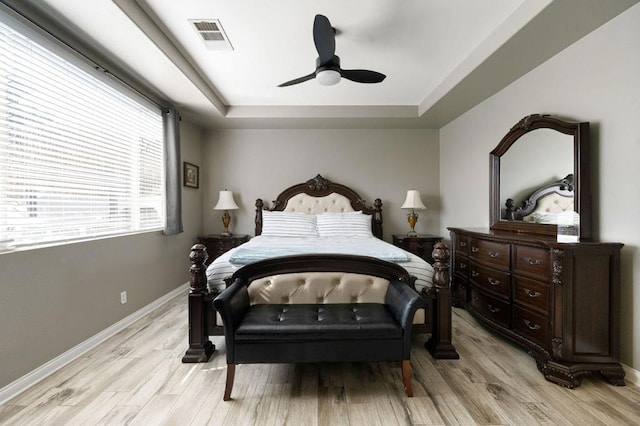 bedroom featuring light hardwood / wood-style floors, a tray ceiling, and ceiling fan