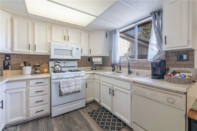 kitchen featuring a drop ceiling, white cabinets, white appliances, and sink