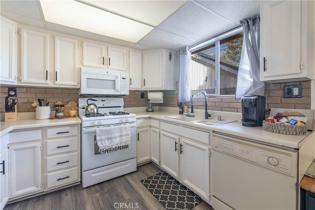 kitchen featuring dark wood-style floors, a sink, white cabinets, and white appliances
