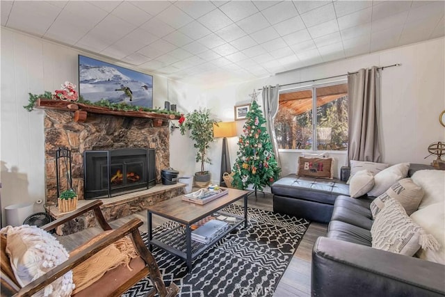 living area with a stone fireplace and wood finished floors