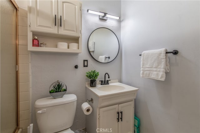 bathroom featuring vanity, toilet, and a shower with door