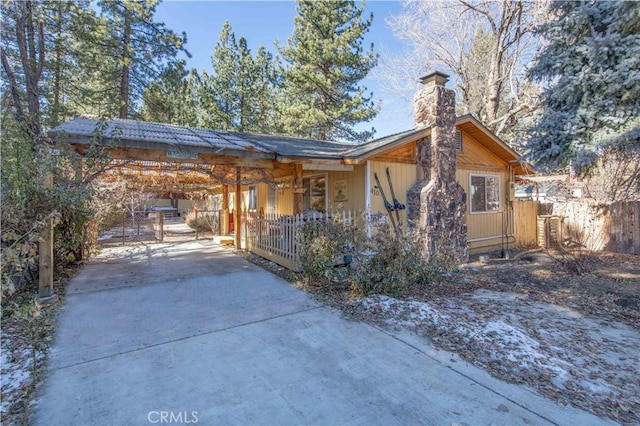 view of front of property featuring an attached carport, driveway, fence, and a chimney