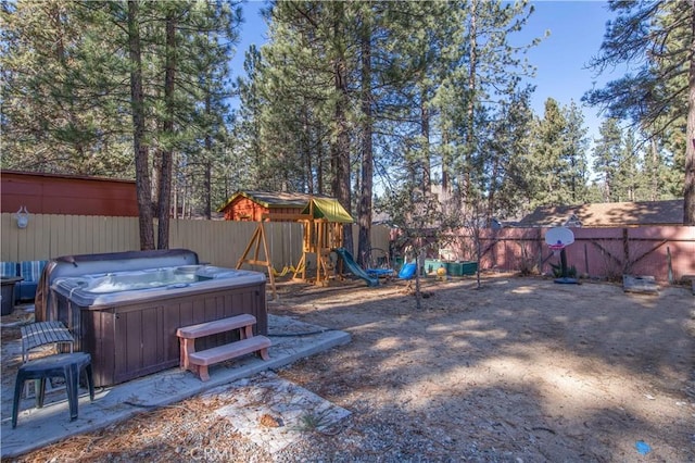 view of yard with a playground, fence, and a hot tub
