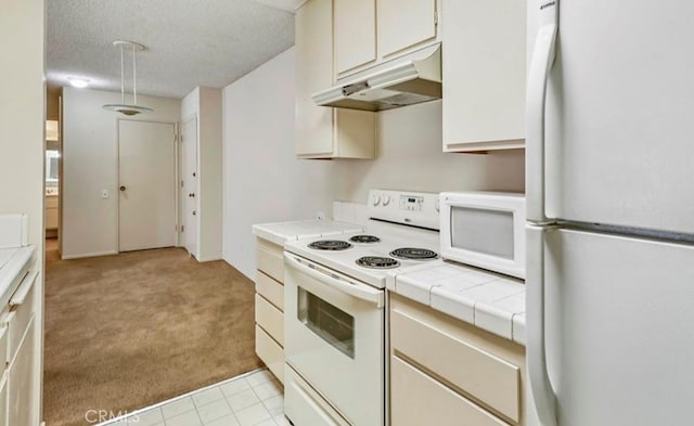 kitchen with white appliances, a textured ceiling, tile counters, and light colored carpet