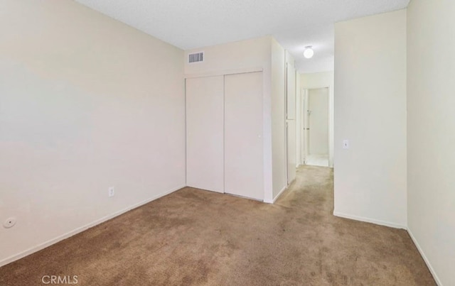 unfurnished bedroom featuring light carpet and a closet