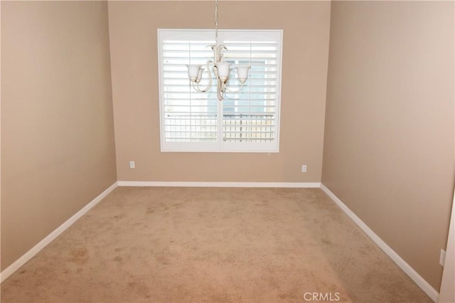 spare room featuring carpet flooring and a chandelier