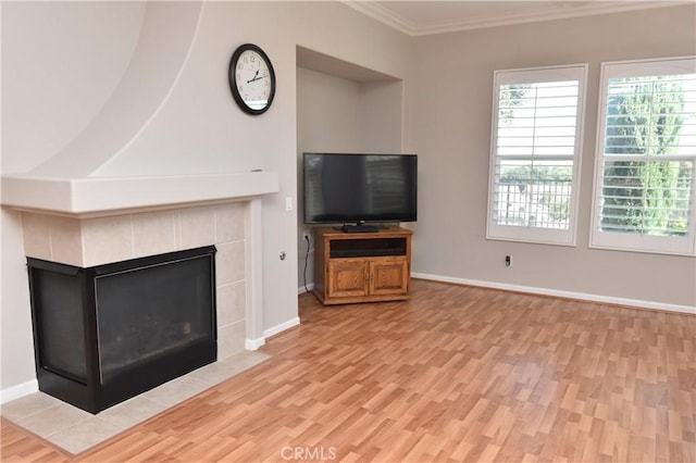 unfurnished living room with light wood-type flooring, crown molding, and a tiled fireplace