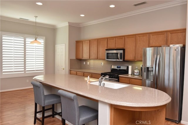 kitchen featuring decorative backsplash, light hardwood / wood-style floors, stainless steel appliances, and a kitchen island with sink