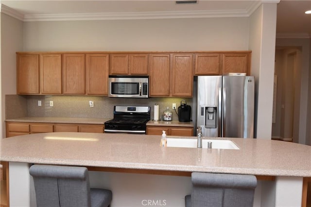 kitchen featuring a kitchen island with sink, sink, crown molding, decorative backsplash, and appliances with stainless steel finishes