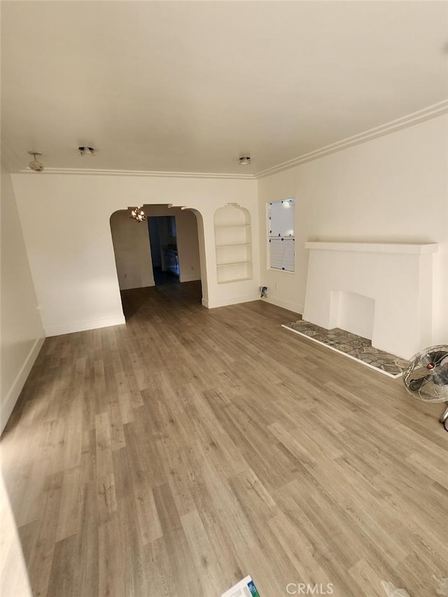 unfurnished living room featuring ornamental molding, hardwood / wood-style floors, and built in features