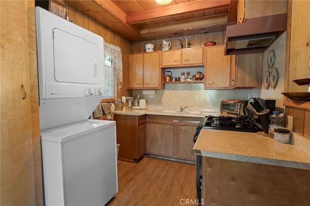 kitchen featuring beamed ceiling, wood ceiling, sink, light hardwood / wood-style flooring, and stacked washing maching and dryer