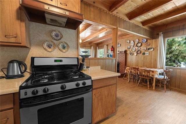 kitchen featuring plenty of natural light, wood walls, gas range, and light wood-type flooring