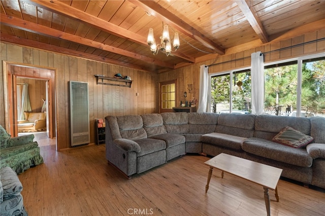 living room featuring wood walls, hardwood / wood-style floors, beamed ceiling, and a chandelier