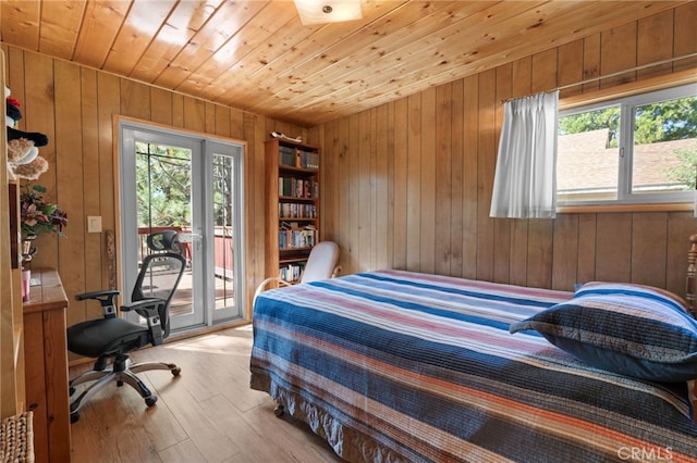 bedroom featuring light wood-type flooring, wood walls, wooden ceiling, and access to outside