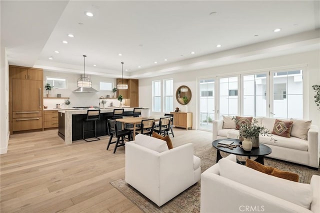 living room with light wood-style floors, recessed lighting, and a raised ceiling