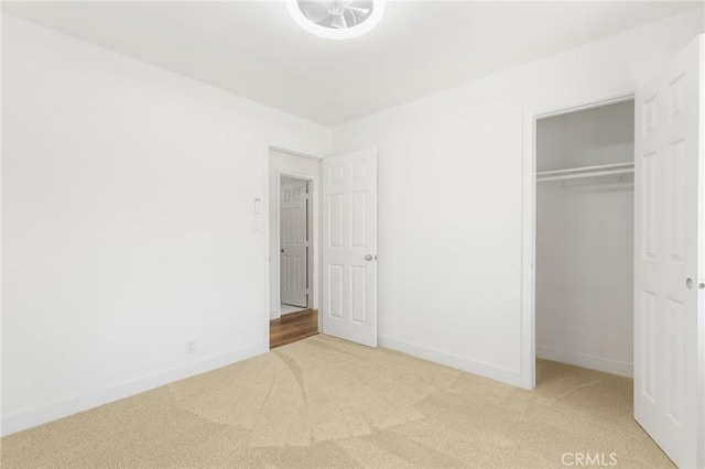 unfurnished bedroom with light colored carpet and a closet