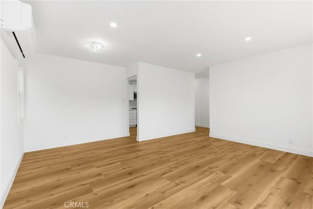 unfurnished room featuring light hardwood / wood-style floors and a wall mounted AC